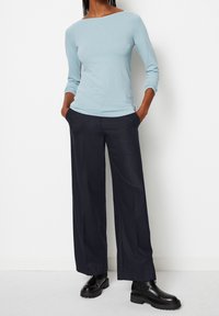 Ljusblå långärmad topp med båtringning, kombinerad med vida mörkblå byxor. Svarta klumpiga ankelboots fulländar outfiten.