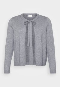 Harmaa neulottu villatakki, jossa on pyöreä pääntie, etutasku ja ribbaus hihansuissa sekä helmassa. Pehmeä rakenne ja avoin etuosan muotoilu.