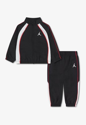 Czarny dres dla malucha z białymi i czerwonymi paskami, kurtka na zamek, elastyczne mankiety oraz biały logo Jumpman na piersi i spodniach.