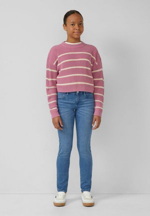 Pull en tricot rose avec des rayures blanches, col rond et texture côtelée. Assorti à un jeans bleu slim et des baskets blanches avec des semelles beige.