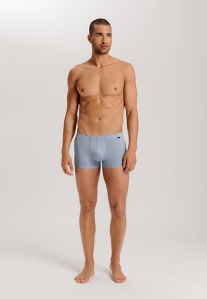 Boxer shorts para hombre de color azul claro, fabricados en un tejido suave, con un diseño ajustado y una cinturilla elástica, llevados por un modelo sin camisa.