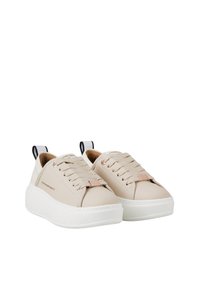 Sneakers in pelle beige con suole bianche spesse, punta arrotondata, lacci piatti e un piccolo logo del marchio. Il tab sul tallone nero crea un contrasto.