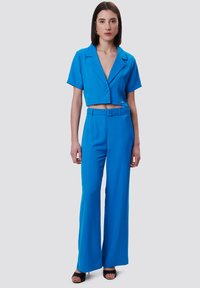 Conjunto de dos piezas azul brillante que incluye una blusa corta de botones con cuello y pantalones de pierna ancha, hechos de una tela suave con una cintura ceñida.