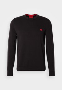 Pull noir à manches longues et col rond avec bords-côtes aux poignets et à l'ourlet, présentant un petit logo rouge rectangulaire sur la poitrine gauche et des détails rouges à l'intérieur du col.