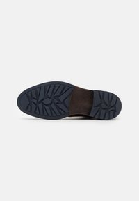 Pantof brown din piele cu un brant de cauciuc texturat de culoare bleumarin, avand un model în zig-zag pentru aderen�ță și o secțiune netedă la toc.