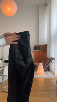 Črne usnjene hlače z visokim pasom, opremljene z zadnjim žepom in dekorativnim šivanjem. Gladka tekstura z oprijetim silhuetom.