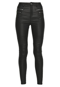 Pantalones de cuero negro con cintura alta. Presentan bolsillos frontales con cremallera y detalles de panel. Silueta ajustada con una textura suave.