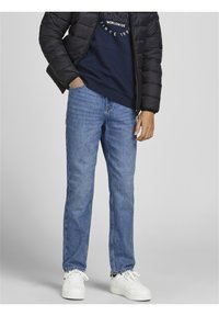 Ljusblå denimjeans, med rak bendesign, som har blekta områden och kontrastsydda detaljer, i kombination med en marinblå huvtröja och en svart pufferjacka.