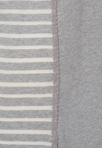 Grått tyg med växlande vita ränder. Har en scalloped kant i ljusgrått längs en kant. Mjuk textur och avslappnad design.