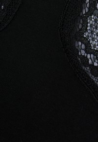 Černý oděv s hladkým materiálem, složitými krajkovými detaily podél výstřihu a přiléhavým střihem. Texturovaný kontrast vytváří vizuální zajímavost.