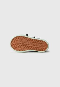 Semelle de chaussure noire avec un fond en caoutchouc orange texturé, présentant un motif en losanges. Le bord est rehaussé d'une finition vert clair pour le contraste.