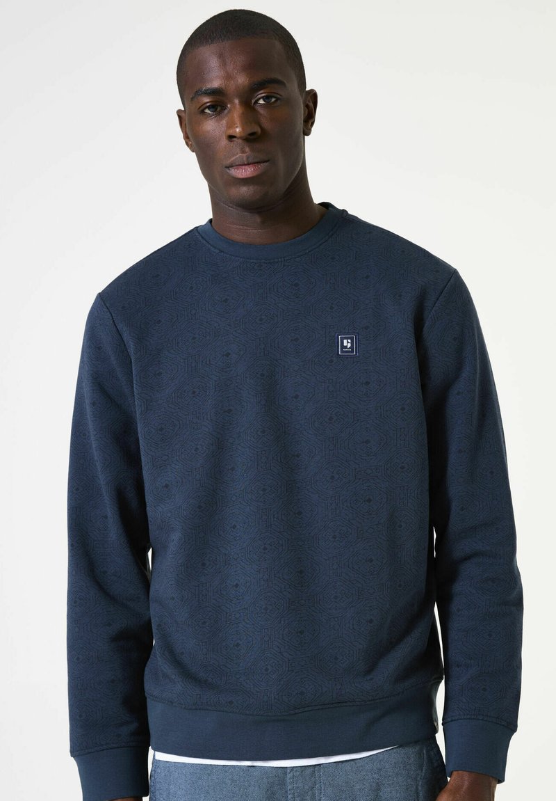 Navyblauwe sweatshirt met een gestructureerd geometrisch patroon, ronde hals en geribbelde manchetten. Bevat een klein logo op de borst.