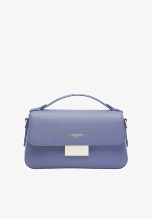 Sac à main en cuir texturé violet avec poignée supérieure, fermoir argenté et logo "Lacoste Paris" sur le rabat avant.