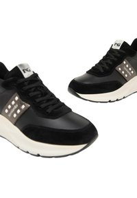 Sneakers in pelle nera e suede con suola bianca, caratterizzati da accenti metallici e un pannello laterale testurizzato con borchie. Design con lacci.