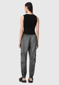 Schwarzes, geripptes Tanktop kombiniert mit grauer Cargohose mit elastischen Bündchen und Seitentaschen, mit glatter Textur und lockerem Sitz.