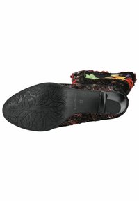 Stivale nero con suola testurizzata decorata da un motivo floreale. Il tessuto superiore è multicolore con disegni intricati e bordi sfilacciati.