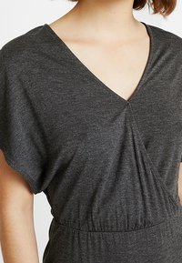 Dunkelgraues, kurzärmeliges Kleid mit V-Ausschnitt und gerafftem Stoff in der Taille, das eine glatte, weiche Textur zeigt.