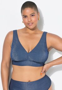 Bralette blu navy con scollatura a V, realizzato in tessuto testurizzato e luccicante. Caratterizzato da spalline larghe e una silhouette aderente e snug.