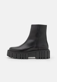 Zwarte leren enkellaarsjes met een grove, geribbelde zool. Gladde afwerking zonder zichtbare hardware of accenten. Strak ontwerp met minimale naden.