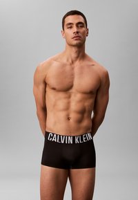 Zwarte katoenen boxershort met een witte "CALVIN KLEIN" logo tailleband, met een aansluitend ontwerp en een gladde textuur.