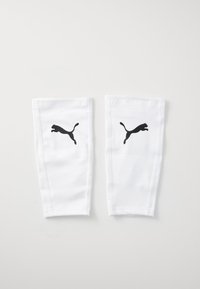 White soccer shin guards made of smooth fabric, featuring a black Puma logo on each guard. Simple design with reinforced stitching.