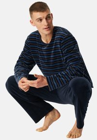 Conjunto de loungewear en azul marino y rayas, que incluye una camiseta de manga larga con rayas anchas y pantalones a juego, fabricado en una suave tela texturada.