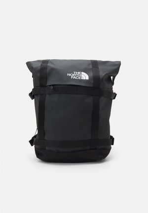 Zwarte roll-top rugzak met verstelbare banden en wit The North Face-logo aan de voorzijde in het midden.