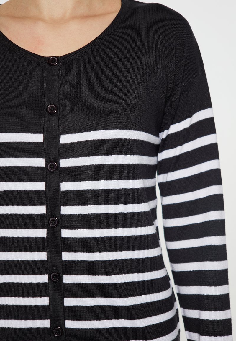 Gestreifter cardigan in Schwarz und Weiß mit langen Ärmeln, rundem Ausschnitt und Knopfleiste. Weicher Strickstoff mit gleichmäßig verteilten horizontalen Streifen.
