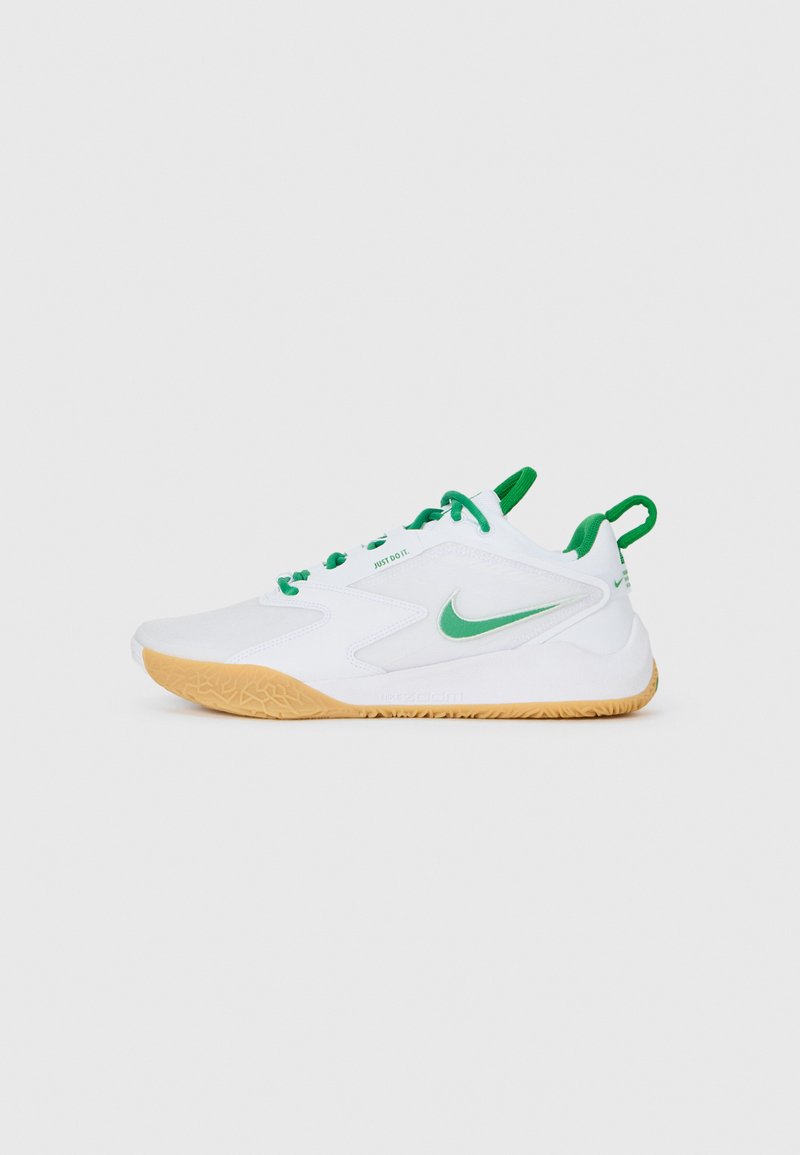 Bílé sportovní tenisky s zelenými akcenty, s texturovanou gumovou podrážkou, aerodynamickým designem a výrazným logem Nike na boku.