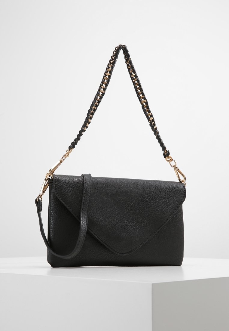 Černé kožené psaníčko s texturou a klopou ve tvaru obálky, odnímatelný černozlatý pletený řetízkový popruh, vystavené na bílém povrchu.