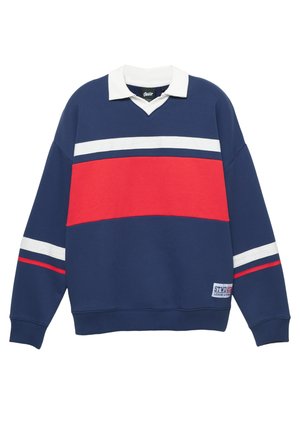 Tmavomodrá mikina s bielym golierom a červeným pruhom. Má horizontálne biele pruhy a logo nášivku na dolnej ľavej strane. Materiál z bavlnenej zmesi.