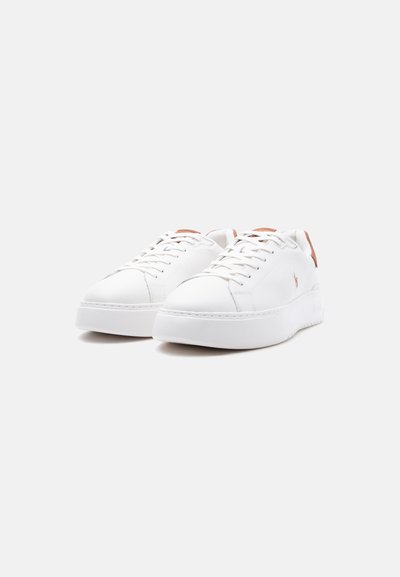 Ζευγάρι λευκών αθλητικών παπουτσιών χαμηλού κόψιμου με λευκά κορδόνια, παχιά σόλα και ταμπά λεπτομέρειες στις ταμπέλες της φτέρνας και το λογότυπο στο πλάι.