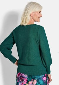 Grüner Strickpullover mit lässiger Passform, gerippten Bündchen und Saum sowie dezentem Glitzereffekt. Mit einem runden Ausschnitt und strukturiertem Stoff.