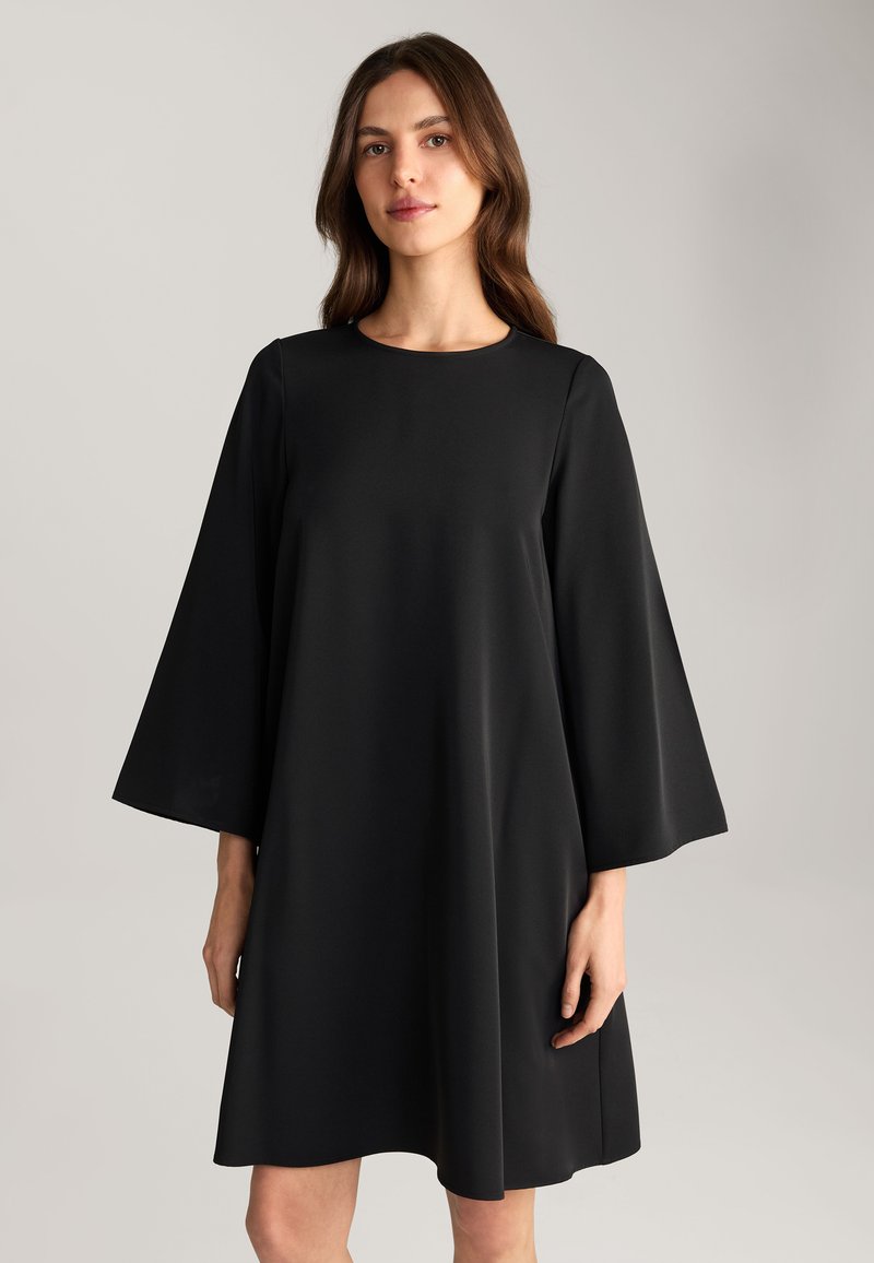 Zwarte jurk met een losse pasvorm, ronde halslijn en wijde klokmouwen. Gemaakt van gladde stof met een rechte zoom. Eenvoudig ontwerp.