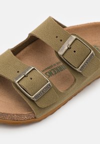 Grön Birkenstock-sandal med texturerade syntetiska remmar, två justerbara spännen i silverfärg och en bekväm korksula.