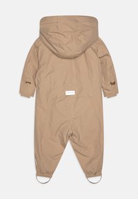 Beige One-Piece-Outwear mit Kapuze, elastischen Bündchen und Ringen an den Knöcheln. Verfügt über eine glatte, matte Oberfläche und ein Logobranding auf der Rückseite.