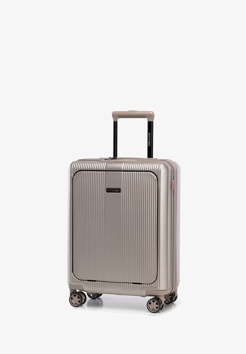 Steifer, goldener Koffer mit vertikalen Rillen, zwei glatten Rädern, einem ausziehbaren schwarzen Griff und einem Logo auf der Vorderseite.