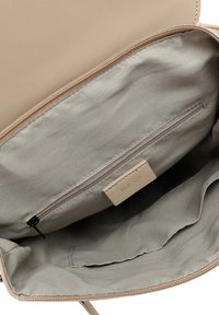 Interno di una borsa beige con rivestimento in morbido tessuto grigio chiaro, dotato di una tasca con zip e un'etichetta con inciso "RUE 09".
