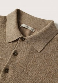 Polo marron tricoté avec un col classique, doté de boutons marron foncé et d'un tissu texturé. Étiquette avec la marque et la taille visible dans le col.