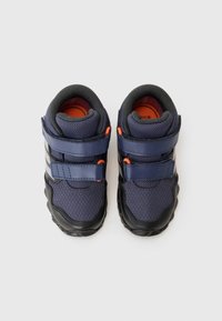 Baskets de sport bleu marine avec semelles noires, en tissu en maille, deux sangles réglables et des accents orange à l'intérieur et sur la quincaillerie.