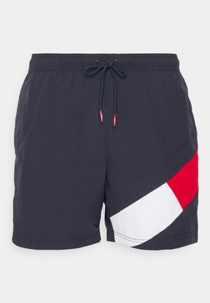 Pantaloni scurți de înot navy cu șnur la talie, având un design diagonal în roșu și alb în colțul din stânga jos. Material ușor și neted.