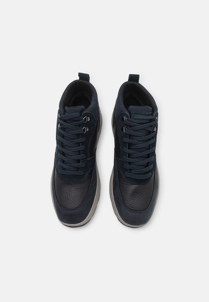 Granatowe sneakersy z połączeniem gładkich i teksturowanych materiałów, z grubymi sznurówkami, srebrnymi oczkami i zaokrągloną podeszwą.