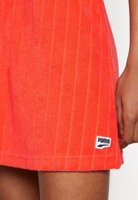 Rode badstof jurk met verticale strepen, voorzien van een zwart-wit Puma-logo op de zoom en een gestructureerde afwerking.