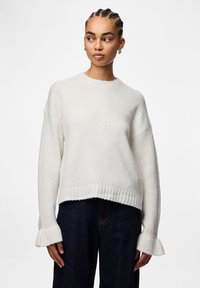 Άσπρο πλεκτό πουλόβερ με ριμπ τελείωμα και φαρδιές μανσέτες, με άνετη εφαρμογή και υφασμάτινη υφή. Συνδυάζεται με σκούρο τζιν.