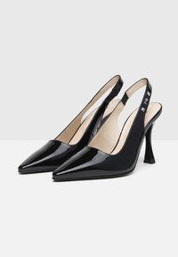 Tacchi slingback in vernice nera con punta affusolata, una decorativa fascetta e un tacco alto scolpito.