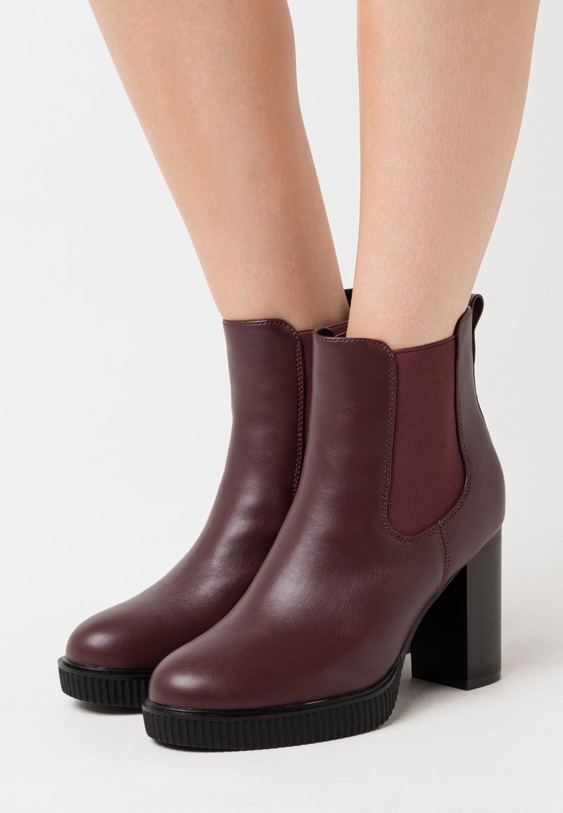Bordowe botki za kostkę wykonane ze skóry, z elastycznymi bocznymi panelami, okrągłym noskiem, teksturowaną gumową podeszwą i słupkowym obcasem.
