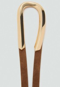 Haarspange aus goldfarbenem Metall mit geschwungenem Design und glatter Oberfläche. Braune Kunstlederriemen sind an der Spange befestigt, um einen sicheren Halt beim Frisieren zu gewährleisten.