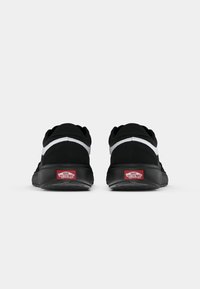 Svarte joggesko med overdeler i semsket skinn og mesh, hvit stripe og tykk sort gummisåle. Har rød "Off the Wall"-logo på hælen.