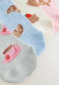 Quatre chaussettes basses colorées avec des motifs tricotés : une tasse à thé rose, un croissant marron, un gâteau à la fraise et un gâteau à étages sur des fonds gris, bleu, crème et rose.