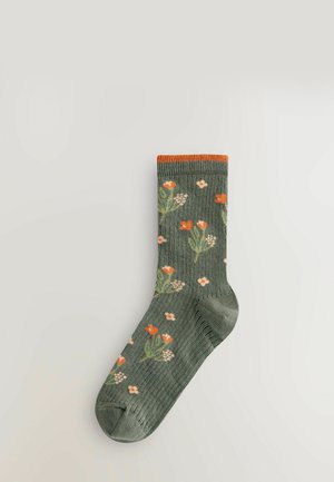 Green socks with a ribbed texture, featuring floral patterns in orange and white, and an orange cuff. Durable fabric for comfort.